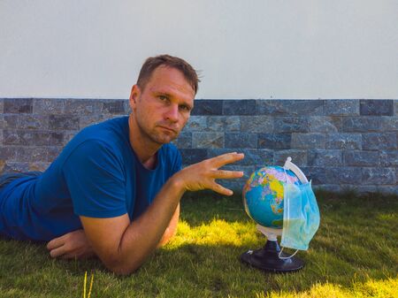 Man wearing Face Mask holding the Earth globe world map in hand. Quarantine yourself to protect spread virus. When can travel again. Epidemic pandemic coronavirus 2019-ncov sars covid-19 virus conceptの写真素材