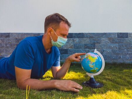 Man wearing Face Mask holding the Earth globe world map in hand. Quarantine yourself to protect spread virus. When can travel again. Epidemic pandemic coronavirus 2019-ncov sars covid-19 virus conceptの写真素材
