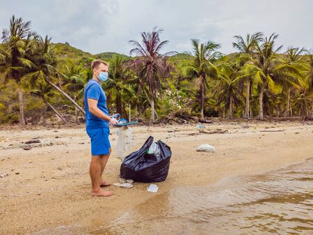 Man in gloves pick up plastic bags that pollute sea. Problem of spilled rubbish trash garbage on the beach sand caused by man-made pollution, campaign to clean volunteer in conceptの写真素材