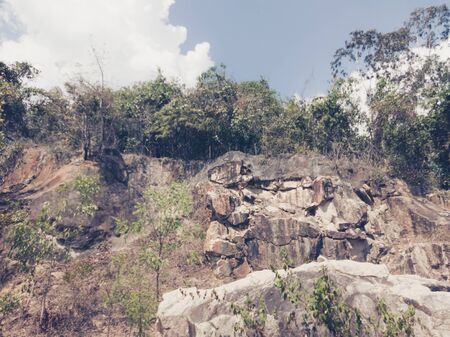 Natural background. Closeup edged shabby cliff cracks. Gray-brown stone rock texture of mountains. Vintage and faded matt style colour in tinted photo. Concept of geolog, mountaineering or hard work.の写真素材
