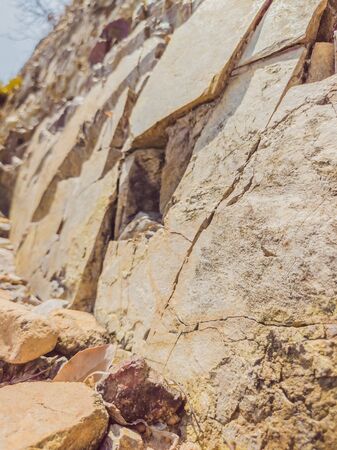 Natural background. Closeup edged shabby cliff cracks. Gray-brown stone rock texture of mountains....