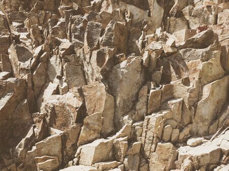 Natural background. Closeup edged shabby cliff cracks. Gray-brown stone rock texture of mountains. Vintage and faded matt style colour in tinted photo. Concept of geolog, mountaineering or hard work.の写真素材