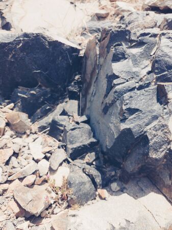 Natural background. Closeup edged shabby cliff cracks. Gray-brown stone rock texture of mountains. Vintage and faded matt style colour in tinted photo. Concept of geolog, mountaineering or hard work.の写真素材