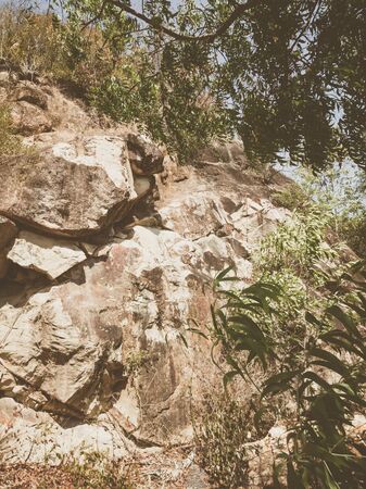 Natural background. Closeup edged shabby cliff cracks. Gray-brown stone rock texture of mountains. Vintage and faded matt style colour in tinted photo. Concept of geolog, mountaineering or hard work.の写真素材