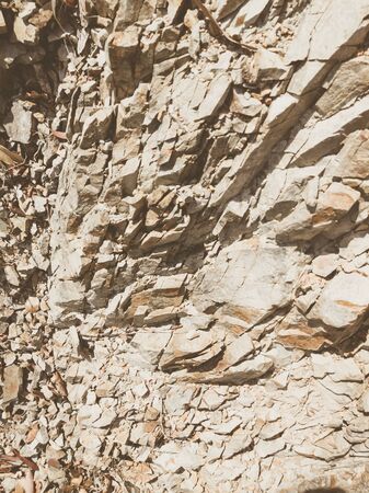 Natural background. Closeup edged shabby cliff cracks. Gray-brown stone rock texture of mountains. Vintage and faded matt style colour in tinted photo. Concept of geolog, mountaineering or hard work.の写真素材