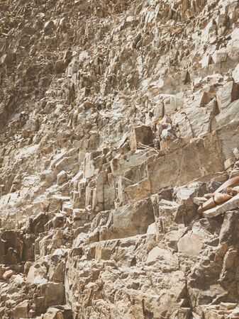 Natural background. Closeup edged shabby cliff cracks. Gray-brown stone rock texture of mountains. Vintage and faded matt style colour in tinted photo. Concept of geolog, mountaineering or hard work.の写真素材