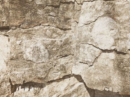 Natural background. Closeup edged shabby cliff cracks. Gray-brown stone rock texture of mountains. Vintage and faded matt style colour in tinted photo. Concept of geolog, mountaineering or hard work.の写真素材