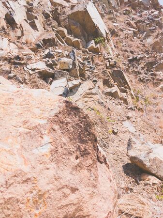 Natural background. Closeup edged shabby cliff cracks. Gray-brown stone rock texture of mountains....