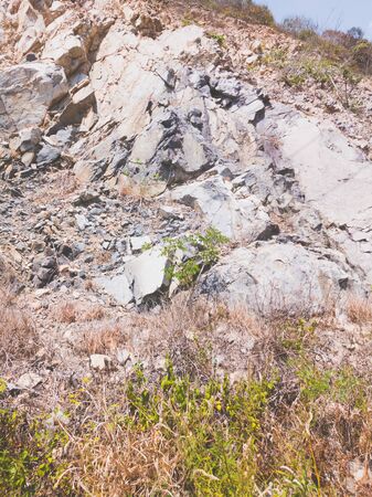 Natural background. Closeup edged shabby cliff cracks. Gray-brown stone rock texture of mountains. Vintage and faded matt style colour in tinted photo. Concept of geolog, mountaineering or hard work.の写真素材