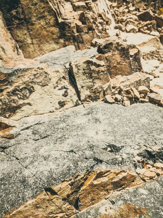 Natural background. Closeup edged shabby cliff cracks. Gray-brown stone rock texture of mountains. Vintage and faded matt style colour in tinted photo. Concept of geolog, mountaineering or hard workの写真素材