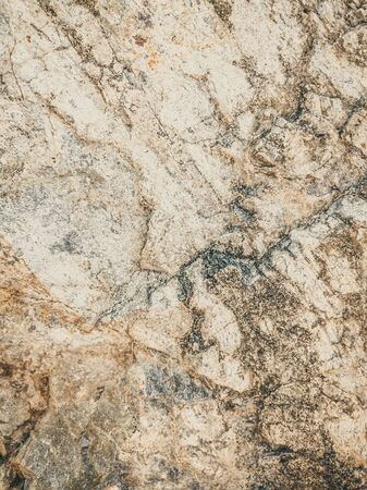 Natural background. Closeup edged shabby cliff cracks. Gray-brown stone rock texture of mountains. Vintage and faded matt style colour in tinted photo. Concept of geolog, mountaineering or hard workの写真素材