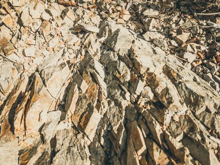 Natural background. Closeup edged shabby cliff cracks. Gray-brown stone rock texture of mountains. Vintage and faded matt style colour in tinted photo. Concept of geolog, mountaineering or hard workの写真素材