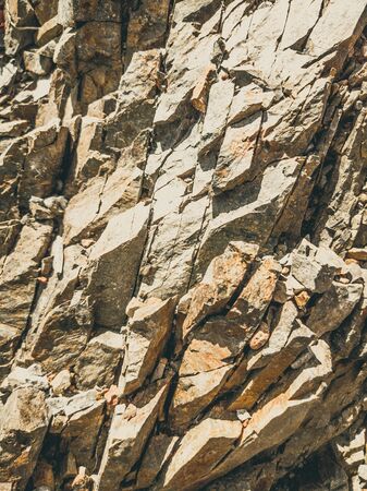 Natural background. Closeup edged shabby cliff cracks. Gray-brown stone rock texture of mountains. Vintage and faded matt style colour in tinted photo. Concept of geolog, mountaineering or hard workの写真素材