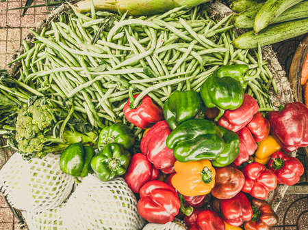 Close-up heap of pile raw red green yellow bell-pepper, green beans and broccoli on a local asia farmers market. Cooking and healthy food concept, vitamins for strong immunity, good nutritional valueの写真素材