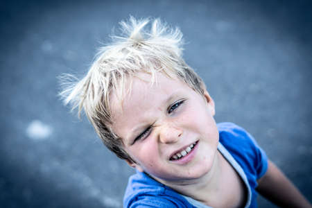 Portrait of a funny happy mischievous cheerful cute blond blue eyed boy making freckles dirty face while playing, laughing. Nursery, happy childhood, education, family relationship conceptの写真素材
