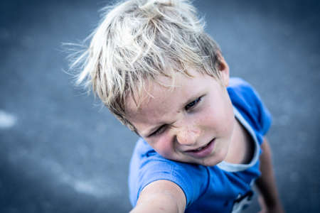 Portrait of a funny happy mischievous cheerful cute blond blue eyed boy making freckles dirty face while playing, laughing. Nursery, happy childhood, education, family relationship conceptの写真素材