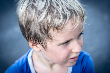 Portrait of a funny happy mischievous cheerful cute blond blue eyed boy making freckles dirty face while playing, laughing. Nursery, happy childhood, education, family relationship conceptの写真素材