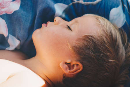 Cute little boy sleep sweetly on pillow with bright morning sunbeams from window, taking a nap. Happy bedtime for kids. Problem of early awakening, late falling asleep, health sleep biorhythmsの写真素材