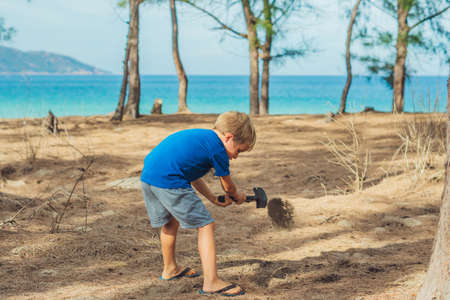Camping people outdoor lifestyle tourists, summer forest near lazur sea. Blond boy play study survival techniques, practice methods to dig the earth with a shovel. Natural children educationの写真素材