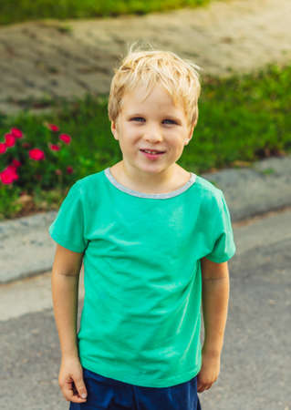 Happy mischievous cheerful cute blond boy with freckles face playing outside, laughing. Behaviour...