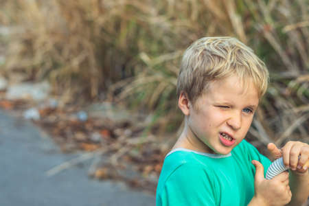 Funny mischievous cute blond boy freckles face squints winks, artistic emotions gesturing. Behaviour education, micro moments joys of happy childhood, compassion toward humanity and society conceptの写真素材
