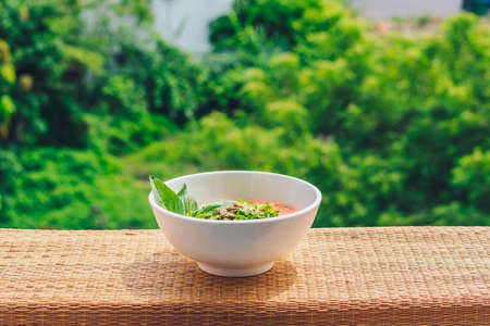 Delicious beautiful raw vegan salad from green leaves mix vegetables in white plate. Cooking recipe Blended tomato carrot cauliflower, cut parsley cilantro dill greenery cucumber, basil pumpkin seedsの写真素材