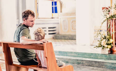 Christian dad tells his son Bible stories about Jesus sitting in kirk. Faith, religious education,...