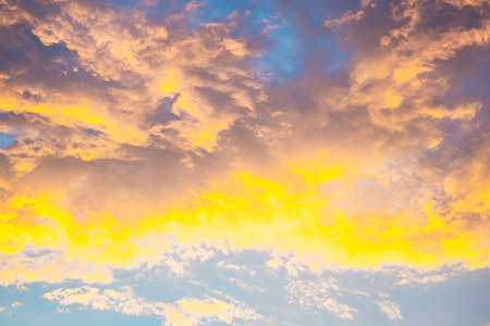 Celestial World concept. Fiery yellow colorful natural bright dramatic sunset sky with clouds. Background natural color of evening cloudscape panorama. Ideal for design wallpaperの写真素材