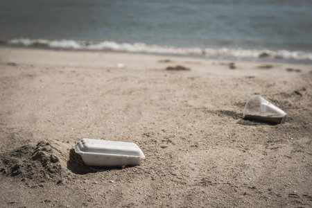 Close trash white foam fast food container for take away service, a lot plastic spilled trash on sea nature beach sand sun day, problem earth ocean pollution contamination, environmental protectionの写真素材