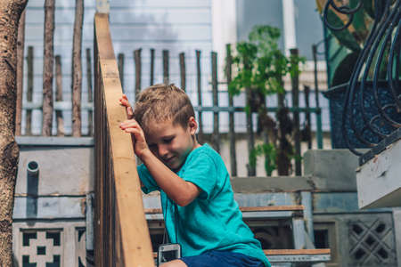 Copy Space lifestyle funny photo little boy move sit wood stairs outside handrails, look for smile...