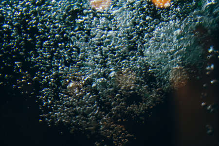 Abstract Macro real air water bubble through glass. Night life style dark blue black depth mystery magic mood space experiment background design. Blue highlight illuminated round light glare effectの写真素材