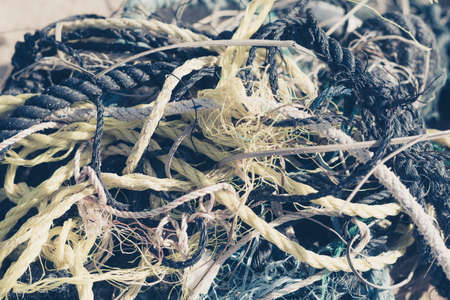E Close multi colored black white yellow old fishing twisted cotton ropes heap pile jumble detail. Concept tangle mess mix mishmash maze, environmental protection rubbish, pale tone more in stockの写真素材