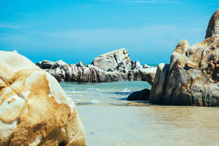 Real nature beauty view background. Sea ocean huge rocks stones cliffs coast bay island landscape sun day blue sky, pale brown orange yellow boulders. Vacation travel recreation. Vintage postcardの写真素材