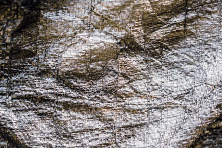 Abstract real fabric surface background. Aluminum Platinum Silver foil Tarpaulin effect with rough texture burlap edge. Futurism 80s retro style new year. Dark Grey brown tone design. More in stockの写真素材
