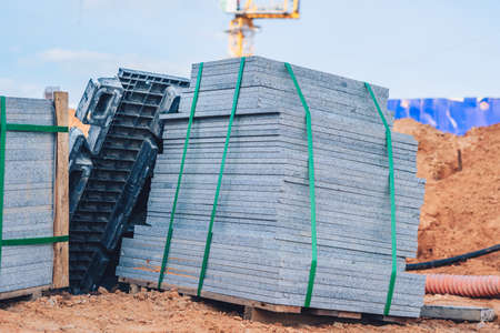 Industrial building cement pressed materials. Concrete block cement brick. Finished products on pallets compactly stacked wooden frame placed on construction site house, rope tape packed open air skyの写真素材