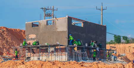 Construction site, steel concrete cement prefabricated house iron rebar, group many team builders doing exterior decor roofless wall building, modern village villa districtの写真素材