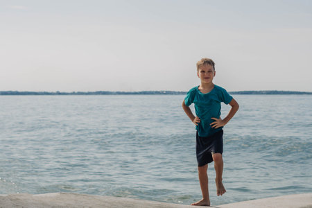 Boy blond smile fun expression bright sun charming nature sport sea beach wet summerの写真素材