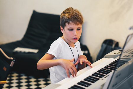 Young boy Portrait sitting at digital piano Playing keyboard focused kid activity indoors press onの写真素材