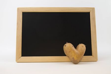 Heart shaped potato in front of a blackboard - copy spaceの写真素材