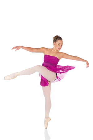 Beautiful young female classical ballet dancer on pointe shoes wearing a black leotard pink stockings and purple dress isolated on a white studio backgroundの写真素材