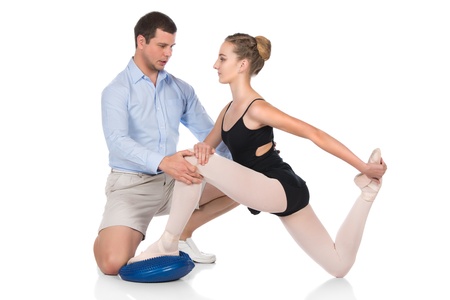 Beautiful female ballet dancer and her physiotherapist isolated on a white background  Ballerina is wearing a black leotard, pointe shoes and pink stockings の写真素材