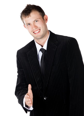 Handsome young successful caucasian businessman wearing a formal black suit, tie and white shirt. He is holding out his hand for a handshake and is smiling.の写真素材