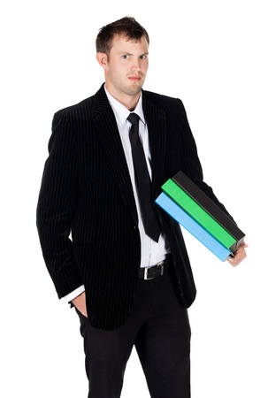 Handsome young successful caucasian businessman wearing a formal black suit, tie and white shirt. The man is typing on and looking at his mobile phone.
The man is holding blue green and black files.の写真素材
