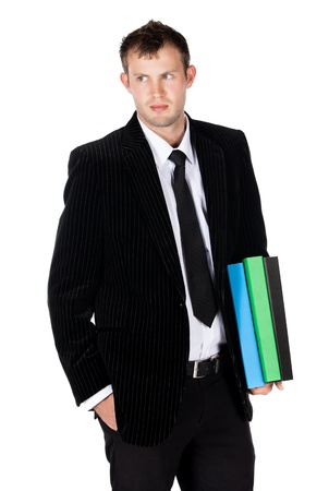 Handsome young successful caucasian businessman wearing a formal black suit, tie and white shirt. The man is typing on and looking at his mobile phone.
The man is holding blue green and black files.の写真素材