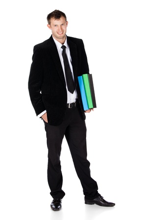 Handsome young successful caucasian businessman wearing a formal black suit, tie and white shirt. The man is typing on and looking at his mobile phone.
The man is holding blue green and black files.の写真素材