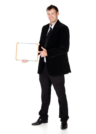 Handsome young successful caucasian businessman wearing a formal black suit, tie and white shirt. The man is holding a small white board and smiling at the camera.の写真素材