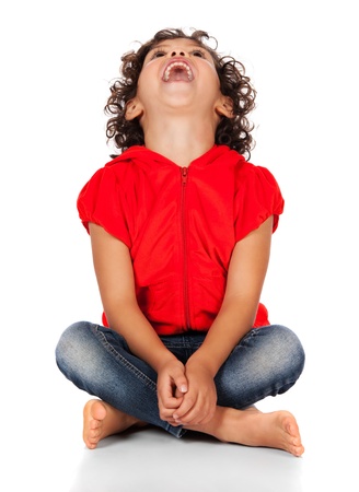 Adorable small caucasian child with curly hair wearing a bright red hooded top and blue jeans. The girl is sitting and smiling at the camera.の写真素材
