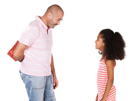 Adorable cute african child with afro hair wearing a white and pink striped dress is getting a gift from her father. The dad is wearing a pink shirt and jeans.の写真素材