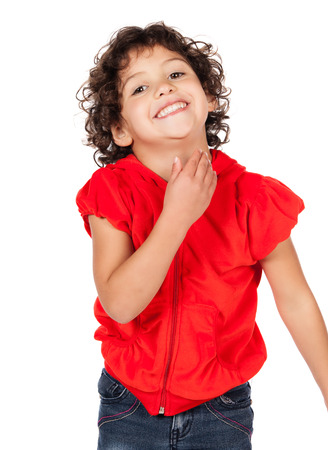 Adorable small caucasian child with curly hair wearing a bright red hooded top and blue jeans. The girl is standing and smiling at the camera.の写真素材