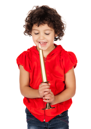 Adorable small caucasian child with curly hair wearing a bright red hooded top and blue jeans. The girl is holding a candle.の写真素材